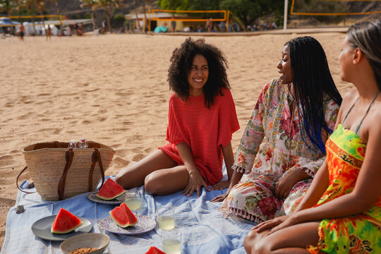 Happy multiracial female friends having fun during beach vacation picnic - Group of young people and summer lifestyle concept