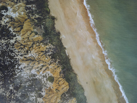Aerial view of the Playa Torre del Loro where golden sands meet the turquoise sea, fringed by rugged cliffs, Mazagon, Andalusia, Spain.