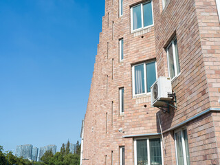 AC unit attached to brick building with white-framed windows