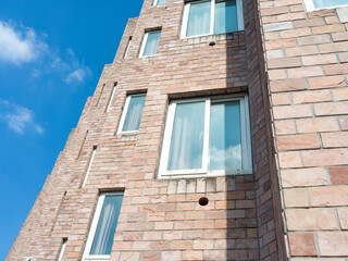 Angled brick building with many windows under blue sky.