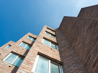 Angled brick building with many windows under blue sky.