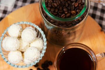 Glass bowl of coconut truffles and black coffee