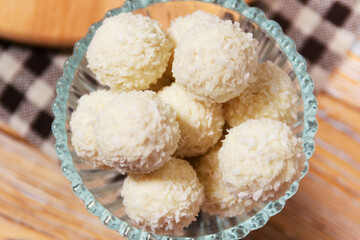 Coconut truffles in glass bowl on wooden table
