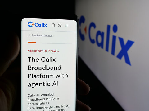 Stuttgart, Germany - 11-14-2025: Person holding cellphone with webpage of US communications company Calix Inc. on screen in front of logo. Focus on center of phone display.