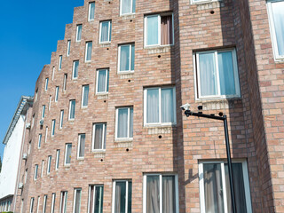 Angled brick building with many windows under blue sky.