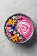 A delightful bowl of pink smoothie, garnished with edible flowers and chia seeds for a vibrant meal.