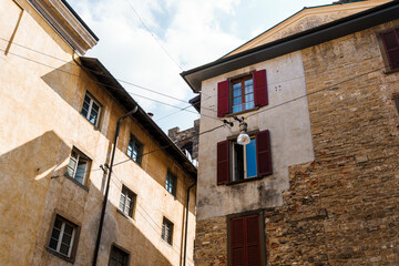 Bergamo's charming architecture with red shutters and aged facades under a blue sky.