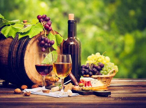 Rustic wine tasting scene with red and white wine grapes cheese and snacks on a wooden table in a vineyard atmosphere