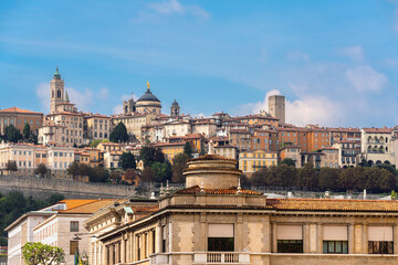 Citta Alta (Upper Town) in Bergamo, Italy against a bright blue sky. A famous view of the city's historic architecture, including the Basilica of Santa Maria Maggiore.