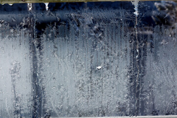 Frosty patterns glow on a chilled windowpane during a cold winter morning in a quiet home setting