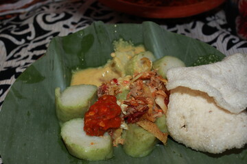 Lontong, a traditional Indonesian rice cake dish, served on banana leaf with spicy peanut sauce and crackers, showcasing local cuisine and cultural heritage.