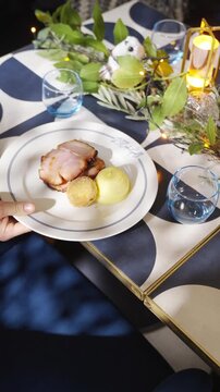 A table with a blue and white patterned top and a black and white patterned tablecloth. There are two wine glasses and a cup on the table. The table is set for a meal with candles