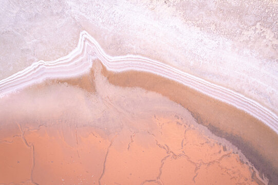Aerial view of salmon pink sands meet stark white salt flats in a mesmerizing dance of contrasting hues and textures, West Ballidu, Western Australia, Australia.