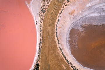 Aerial view of contrasting pink and brown salt lakes divided by a strip of golden land, creating a stunning natural abstract, West Ballidu, Western Australia, Australia.