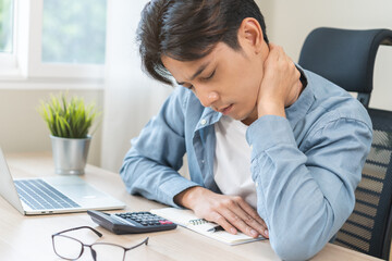 Body muscles stiff problem, ache asian young man pain neck and shoulder while sitting work on chair at home, male holding massaging rubbing, hurt or sore body. Healthcare people, office syndrome.