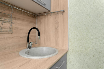 A round kitchen sink with a faucet is built into a wood-textured countertop