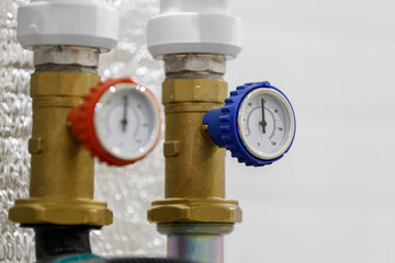 Red and blue thermometers on brass fittings show the temperature in the system