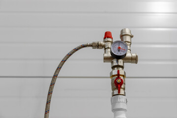 A plumbing assembly with a pressure gauge and a safety valve to control the pressure in the system