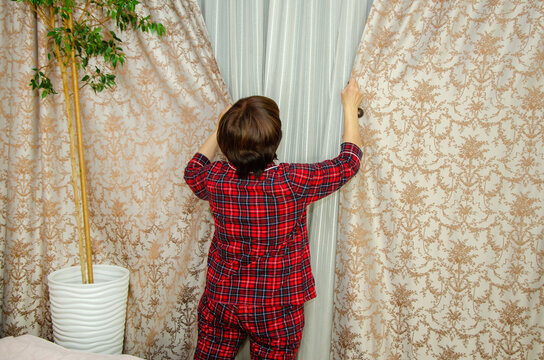 Woman closing curtains in bedroom before sleep
