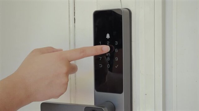Hand entering security code on electronic door lock and opening the door.