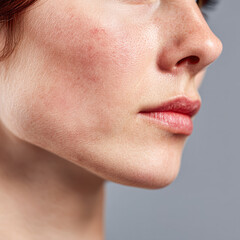 Obraz premium Close-up of a woman's face highlighting smooth skin, natural features, and subtle makeup against a neutral background.