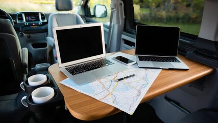 Mobile workspace setup in car with laptops, smartphone and map on wooden table for travel and remote work inspiration