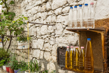Hausfassade mit Naturstein und Plastikflaschen mit Öl und Raki, Berat, Bezirk Berat, Albanien