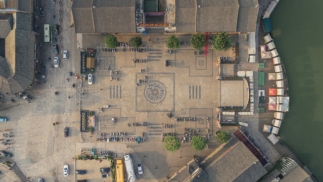 Aerial view of a serene square with geometric pavement patterns bordered by aged buildings and a waterfront, Honghe Hani and Yi Autonomous Prefecture, Yunnan, China.