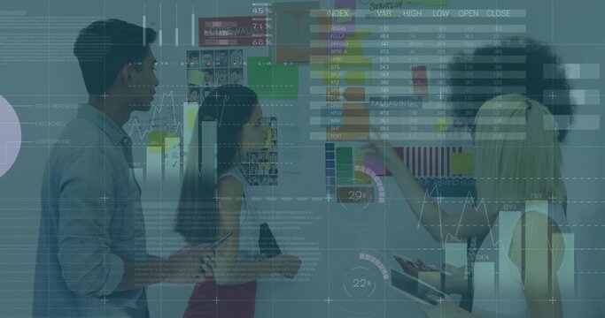 Reviewing team in business attire pointing at chart wall, with tablets and data overlays - Powered by Adobe