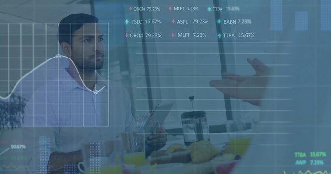 Holding tablet, seated Asian man in business attire reviewing charts at office breakfast, croissant