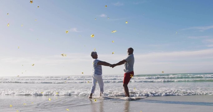 Holding couple leaning in shallow surf at beach, red shorts striped top, gold stars sparkling