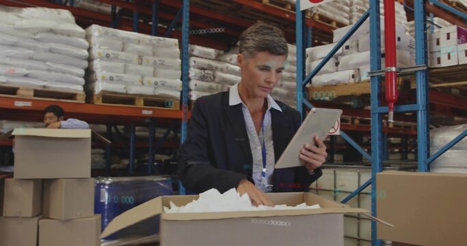 Inspecting manager in blazer and collared shirt using tablet, checking box at warehouse, pallets