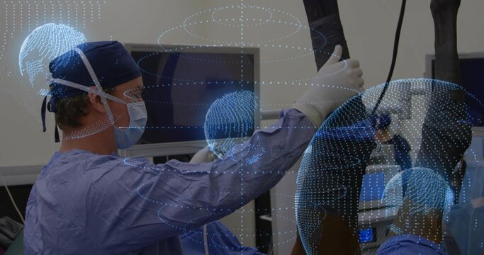 Holding endoscope, surgeon in gown viewing monitors in operating room, globe hologram, copy space - Powered by Adobe