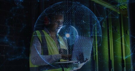 Holding laptop, technician typing in data center, wearing hi-vis vest and red muffs, hologram