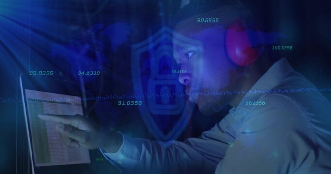 Pointing IT pro viewing laptop table in dim blue hub, shirt, red headset, shield numeric overlays