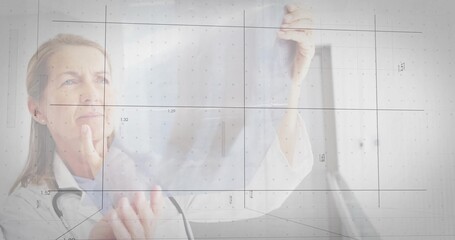 Examining senior clinician in white coat with stethoscope holding film in clinic, showing grid