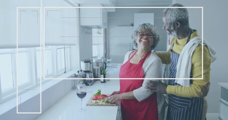 Chopping couple wearing red and striped aprons at counter, cutting board with tomatoes, copy space