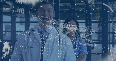 Posing physician and nurse wearing lab coat, blue scrubs, stethoscopes, showing world map in clinic