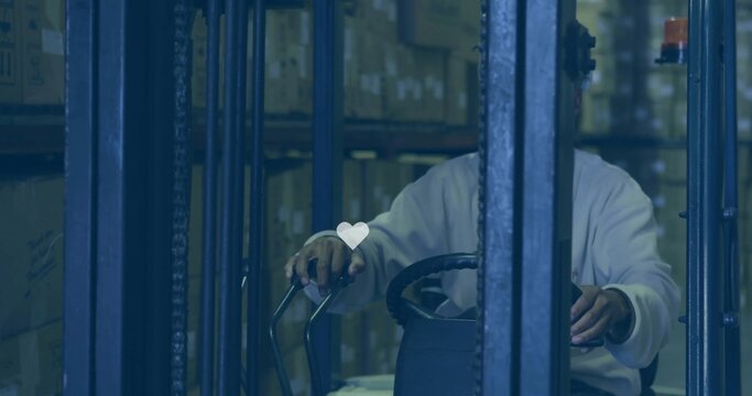 Operating forklift, male steering controls in warehouse aisle with heart overlay, wearing light top