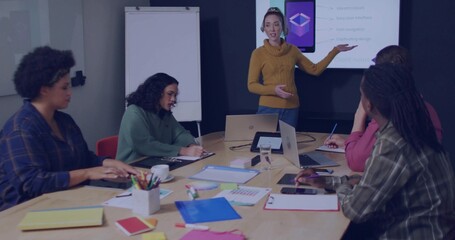 Leading woman in mustard sweater pointing at slide in meeting room with laptops, copy space
