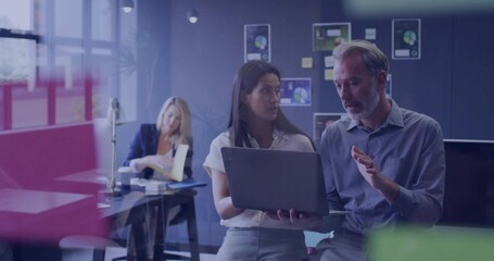 Discussing mature coworkers in business-casual clothing pointing at laptop in modern office, charts