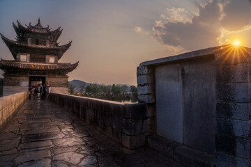 Honghe, China - 22 November 2025: View of the ancient Honghe bridge, its stone reflecting the last light of day as people stroll towards the ornate pavilion.
