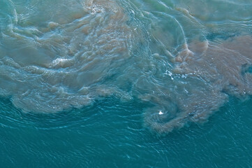 Dirty slag and oily water stirred up by ship propellers in the container port. Environmental pollution caused by heavy fuel oil from the container shipping industry and transport. 