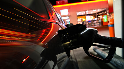 Gas pump or petrol station garage nozzle by petrol station with mini market 24 hours open on city lights night. 