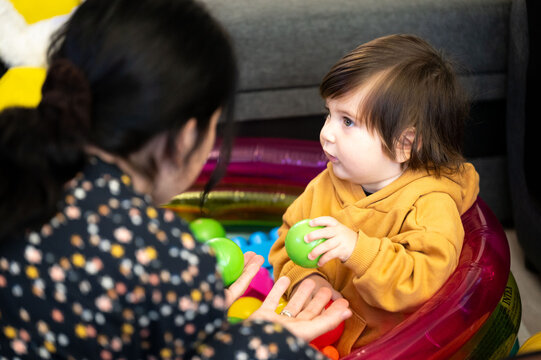 Little one's colorful conversation early afternoon with caregiver in playroom filled with childhood glee and engaging social interaction