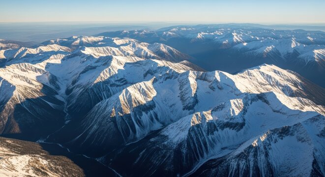Aerial view of vast snowy mountain ranges under a clear blue sky