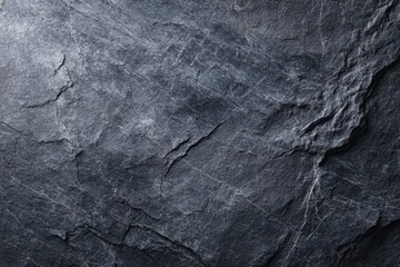 Dark, textured slate surface with cracks and crevices, close-up view