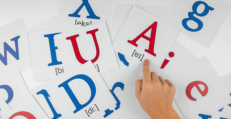 English language learning: child pointing at a card with letter A and phonetic transcription