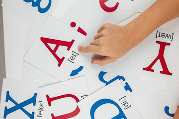 English language learning: child pointing at a card with letter A and phonetic transcription