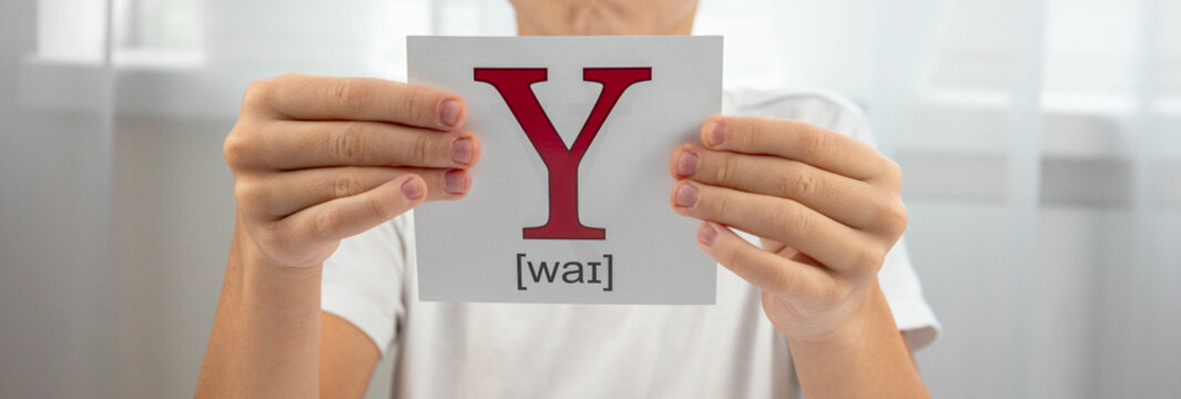Boy presenting a flashcard with the letter Y and its phonetic transcription for studying